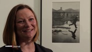 Die Direktorin des Bucerius Kunstforums steht strahlend neben einer Fotografie von Bresson. © Screenshot 