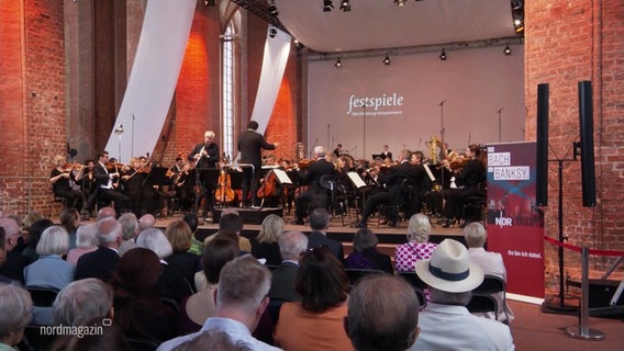 Menschen hören einem Konzert in einer Kirche zu. © Screenshot 