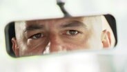 Im Rückspiegel eines Autos sieht man die Augen eines Mannes. © Screenshot 