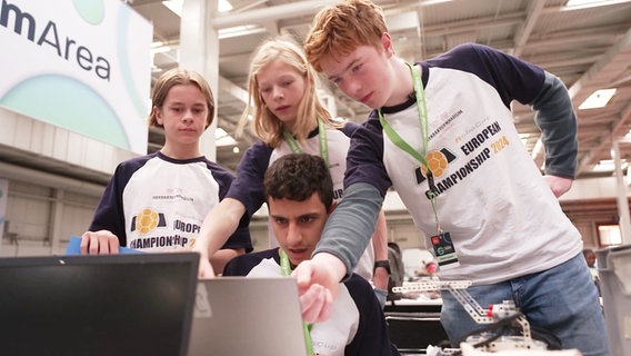 Vier Jugendliche sind um einen Laptop versammelt. Vor ihnen steht außerdem ein Lego-Roboter. Sie tragen Trikots mit der Aufschrift "Europe Championship 2024". © Screenshot 