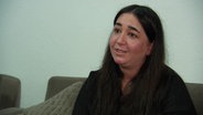 Familienbegleiterin Aishe Yilmaz im Interview. Sie trägt eine schwarze Bluse und hat langes, offenes braunes Haar. © Screenshot 
