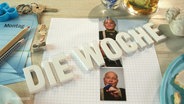 Auf einem Tisch liegen Notizzettel, kleine Passbilder und Stift. Dreidimensionale weiße Blockbuchstaben bilden den Schriftzug "Die Woche". © Screenshot 