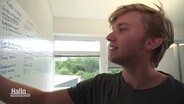 Der 21-jährige Unternehmer Arian Jung schreibt etwas an eine Tafel. © Screenshot 