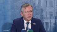 Finanzminister Geue spricht bei einer Pressekonferenz. © Screenshot 