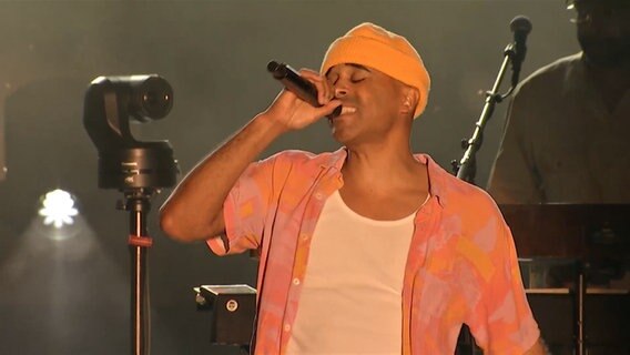 Der Berliner Musiker Patrice singt gefühlvoll in ein Mikrofon auf der Kieler Woche 2024. © Screenshot 