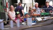 Kinder stehen an einer Miniatureisenbahn. © Screenshot 