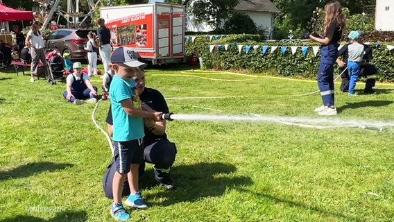 Ein Kind spielt auf dem Kinderfest mit einer Wasserspritze. © Screenshot 