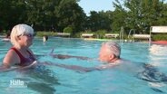 Eine Frau bringt einem Mann das Schwimmen bei. © Screenshot 