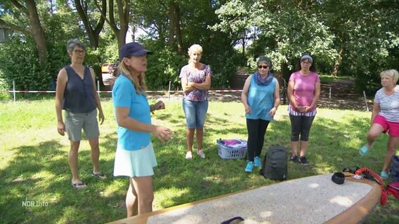 Mehrere Frauen stehen um ein stand-up-Paddle-Board herum © Screenshot 