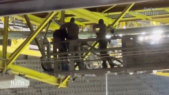 SEK-Beamte nehmen eine vermummte Person im Gerüst des Stadiondachs fest. © Screenshot 