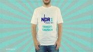 Ein Mann hat ein weißes T-Shirt an, auf dem in blauer Schrift "NDR 1 Radio MV Trikottausch" steht. © Screenshot 