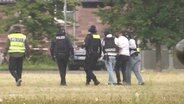 Ein mutmaßlicher Kriegsverbrecher aus Syrien wird von mehreren Polizeibeamten festgenommen. © Screenshot 