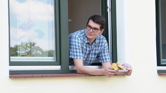 Ein Mann hält einen Teller mit Kuchen in den Händen. © Screenshot 