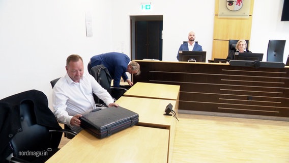 Mehrere Menschen sitzen in einem Gerichtssaal. © Screenshot 