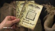 Jemand hält eine Spielkarte mit der Aufschrift "Wie heißt Hamburgs Burg?" in der Hand © Screenshot 