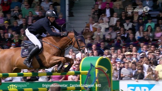 Springreiter André Thieme springt mit seinem Pferd über ein Hindernis. © Screenshot 