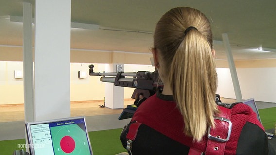 Eine junge Sportschützin steht an einem Schießstand. © Screenshot 