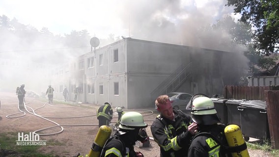 Feuerwehrleute an der qualmenden Geflüchtetenunterkunft in Buchholz. © Screenshot 