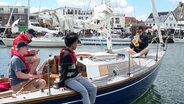 Ein Musiker sitzt auf einem Boot und macht Musik mit seiner Trompete. © Screenshot 