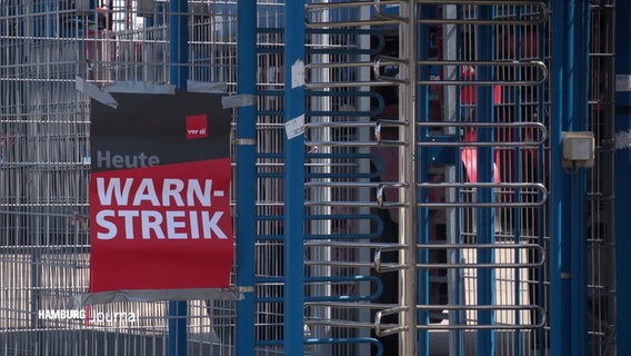 Ein Schild mit der Aufschrift "Warnstreik" an einem Eingang mit Drehkreuz. © Screenshot 