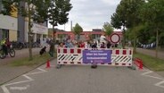 Kinder hinter einer Straßensperrung vor einer Schule. © Screenshot 