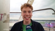 Der Reporter Marek Walde moderiert auf einem Riesenrad. © Screenshot 