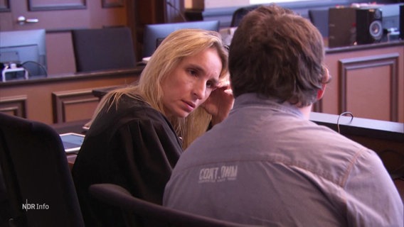 Der Angeklagte, ein korpulenter Mann mit braunen Haaren, spricht vor Gericht mit seiner Verteidigerin, die sich in seine Richtung dreht. © Screenshot 