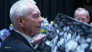 John Neumeier hält während seines Abschieds auf der Nijinsky-Gala ein großes schwarz-weiß-Foto in den Händen. © Screenshot 