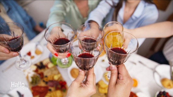 Mehrere Personen stoßen mit alkoholischen Getränken an. © Screenshot 