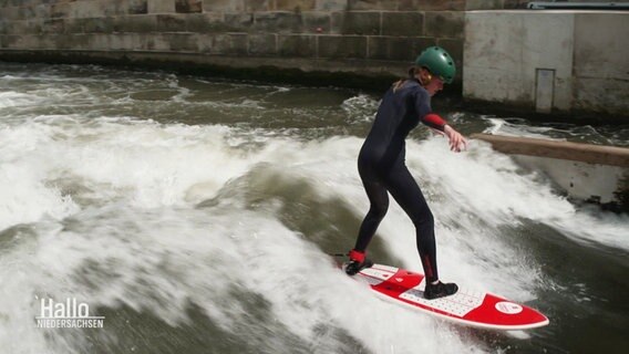 Ein Mädchen surft in einem Fluss. © Screenshot 