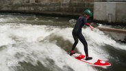 Ein Mädchen surft in einem Fluss. © Screenshot 