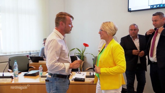 Eine Frau überreicht einem Mann eine Blume. © Screenshot 