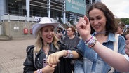 Junge Frauen zeigen sich gegenseitig ihre Taylor-Swift-Armbänder. © Screenshot 