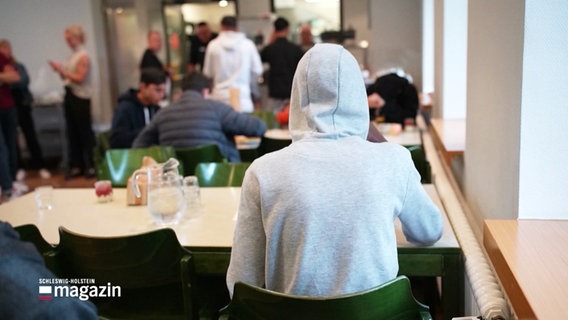 Ein Jugendlicher mit Kapuzenpullover sitzt an einem Tisch. © Screenshot 