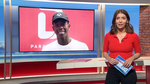 Moderatorin Lena Mosel im Studio, links von ihr eingeblendet ein Foto von Basketball-Weltmeister Dennis Schröder. © Screenshot 