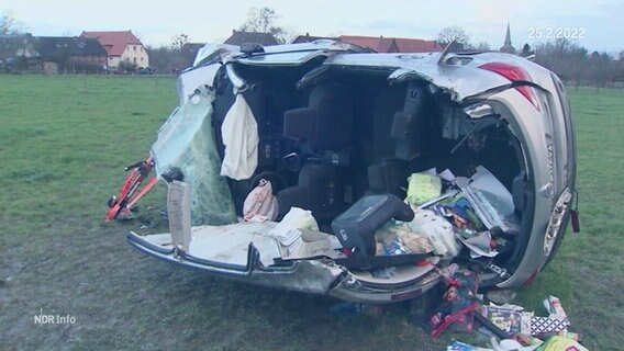 Ein schwer verunglücktes Auto liegt auf der Seite, das Dach wurde aufgeschnitten, Gegenstände sind herausgefallen. Ein Kindersitz liegt umgekippt im Wagen. © Screenshot 
