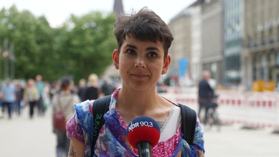 Ein junge Frau spricht ins Mikrofon mit der Aufschrift NDR 90,3 © Screenshot 