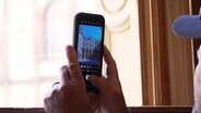 Ein Mann fotografiert das Schweriner Residenzensemble mit seiner Handy-Kamera. © Screenshot 