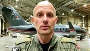 Ein dänischer Soldat steht vor einem Flugzeug. © Screenshot 