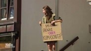 Luisa Neubauer ist mit einem Protestschild auf eine Laterne geklettert. © Screenshot 