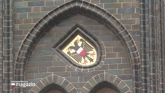 Ein Wappen mit Adler auf einer schwarzen Wand. © Screenshot 