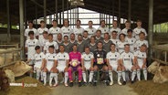 Fussballer eines Dorfvereins stehen im Stall für ein Foto zusammen. © Screenshot 