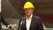 Olaf Scholz bei einer Rede, er trägt einen gelben Sicherheitshelm. © Screenshot 