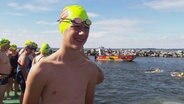 Julius Michel mit Schwimmbrille und neongelber Badekappe vor dem Start. © Screenshot 