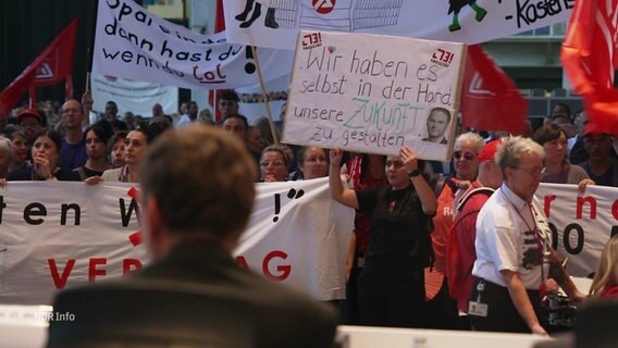 Gewerkschaftsmitglieder bei einer Protestaktion auf der Betriebsversammlung von Volkswagen. © Screenshot 
