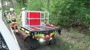 Hinter einem Löschroboter laufen zwei Feuerwehrmänner. © Screenshot 