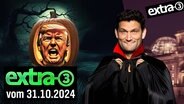 Ein Kürbis mit Donald Trump Gesicht in einer gruseligen Atmosphäre. Daneben Christian Ehring in einem Vampirkostüm. (extra 3 vom 31.10.2024 im Ersten) © NDR 