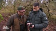 Zwei Jäger schauen zusammen auf ein Samrtphone im Wald. © Screenshot 