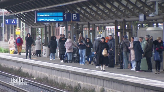 Menschen warten auf einem Bahnsteig. © Screenshot 