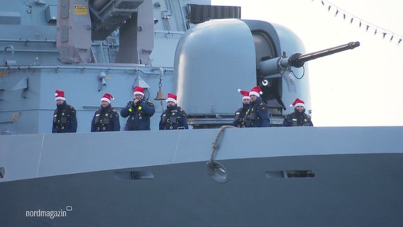 Am Bug einer Marineschiffes stehen Soldatinnen und Soldaten mit Nikolausmützen. © Screenshot 